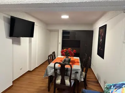 a dining room with a table with chairs and a television at 2- Amplio Departamento remodelado en Miraflores in Lima