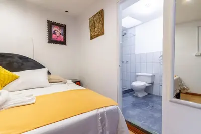 a bedroom with a bed and a bathroom with a toilet at Hotel Campanario in Cusco