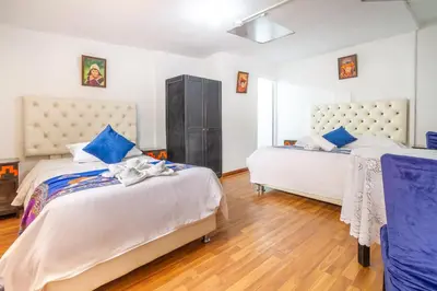 a bedroom with two beds with blue pillows at Hotel Campanario in Cusco