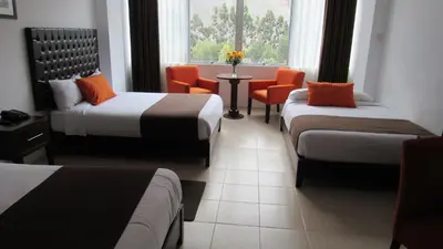 a hotel room with two beds and a table and chairs at Guizado Portillo Hacienda & Resort in Lunahuaná