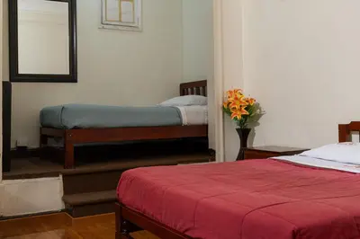 a bedroom with two beds and a vase of flowers at Hospedaje Santa Rosa- Centro Histórico in Lima