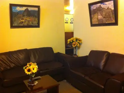 a living room with a couch and a table with flowers at Hostal Alfredo's Palace in Cusco