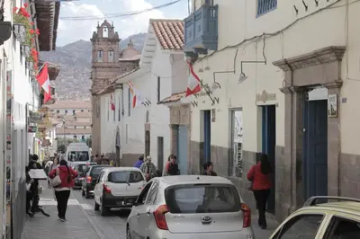 a street with cars and people walking down the street at Hostal Alfredo's Palace in Cusco
