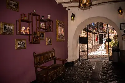 a room with an archway with a chair and pictures on the wall at Intro Hostels Cusco in Cusco