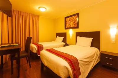 a hotel room with two beds and a desk at Casa Suyay in Lima