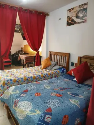 two beds in a bedroom with red curtains at Inti Hostel Airport in Lima