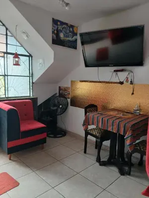 a living room with a table and a tv on the wall at Inti Hostel Airport in Lima