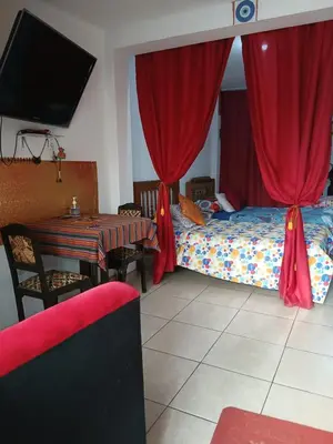 a bedroom with a bed and a table and a television at Inti Hostel Airport in Lima