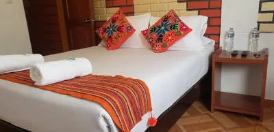 a bedroom with a white bed with pillows on it at Quipu Hostal in Machu Picchu