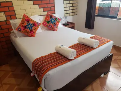 a large white bed with two towels on it at Quipu Hostal in Machu Picchu