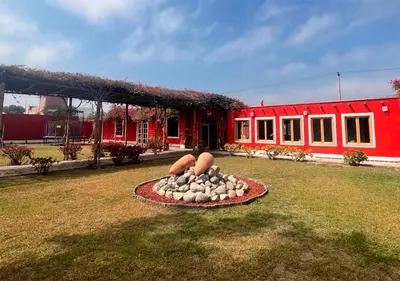 a red house with a statue in the grass at La Estancia Chincha Hotel in Chincha Alta