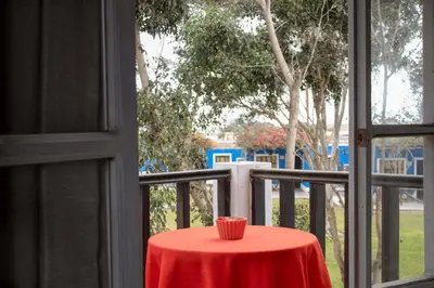 a red table with a red cup on a balcony at La Estancia Chincha Hotel in Chincha Alta