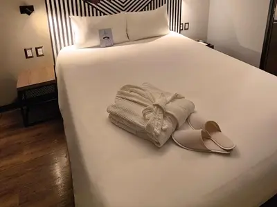 a bed with a pair of sandals and a robe at ibis styles Lima San Isidro in Lima