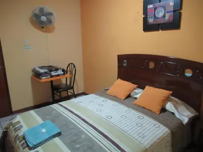 a bedroom with a bed with a fan on the wall at Kurmi Hostel Lima Airport in Lima