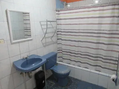 a bathroom with a blue toilet and a shower curtain at Kurmi Hostel Lima Airport in Lima