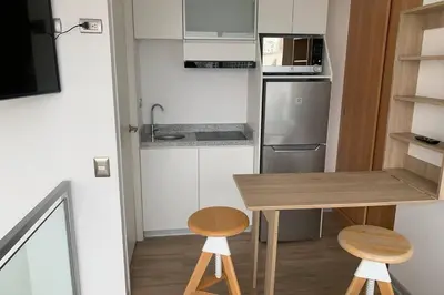 a small kitchen with a wooden table and two stools at Barranco Penthouse ocean boardwalk in Lima