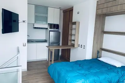 a small bedroom with a blue bed and a kitchen at Barranc Group Penthouse in Lima