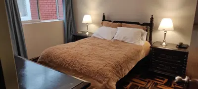 a bedroom with a bed with two night stands and two lamps at San Borja Habitación amoblada independiente dentro de departamento amoblado tipo ROOMMIE Tv42 Cerca JockeyPlaza in Lima