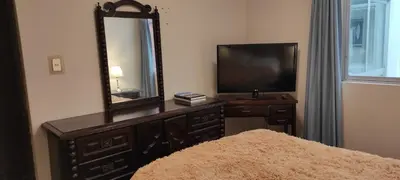 a bedroom with a dresser with a mirror and a television at San Borja Habitación amoblada independiente dentro de departamento amoblado tipo ROOMMIE Tv42 Cerca JockeyPlaza in Lima