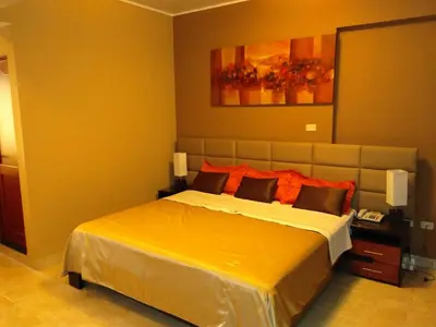 a bedroom with a large bed with orange pillows at Gran Hotel Ica in Ica