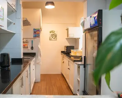 a kitchen with white cabinets and a refrigerator at The Secret Garden Hostel in Lima