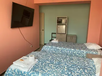 a hotel room with two beds and a flat screen tv at Rooms MD in Huancayo