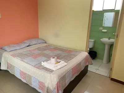 a bedroom with a bed with a sink and a toilet at Rooms MD in Huancayo