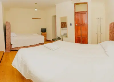 a hotel room with two beds and a mirror at Hostal Chasky in Cusco