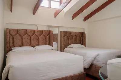a bedroom with two beds and a window at Hostal Chasky in Cusco