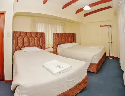a hotel room with two beds with white sheets at Hostal Chasky in Cusco