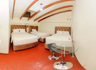 a room with two beds and a glass table at Hostal Chasky in Cusco
