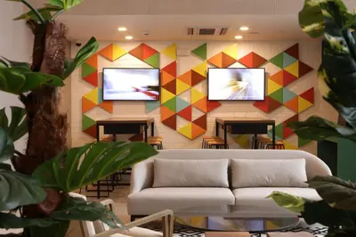 a living room with a couch and two televisions on a wall at Casa Andina Standard Benavides in Lima