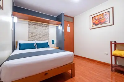 a bedroom with a large bed with blue pillows at Hotel Savoy Ica in Ica