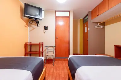 a hotel room with two beds and a flat screen tv at Hotel Savoy Ica in Ica