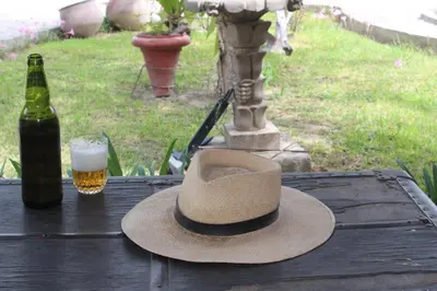 a hat and a glass of beer on a table at Hostal Loma Blanca in Ica
