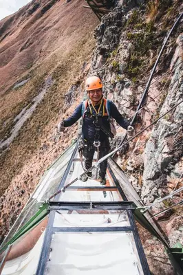 a man walking across a rope bridge on a mountain at Vertical Sky Suites in Ollantaytambo