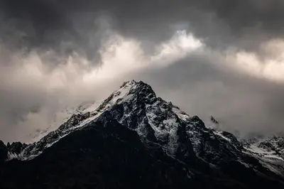a snow covered mountain under a cloudy sky at Vertical Sky Suites in Ollantaytambo