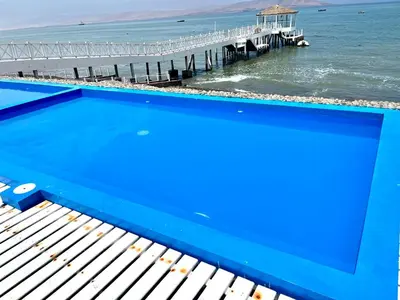 a swimming pool next to the ocean with a pier at Paracas Paracas! Vista Bahia - Sotavento 201 T 6 in Paracas