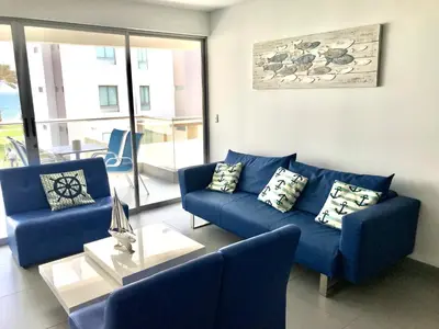a living room with a blue couch and two chairs at Paracas Paracas! Vista Bahia - Sotavento 201 T 6 in Paracas