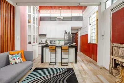 a living room with a couch and a kitchen at Loft abierto y moderno & Aire acondicionado in Lima