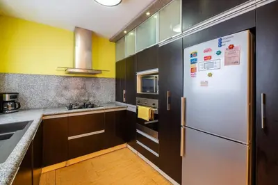 a kitchen with a white refrigerator and wooden cabinets at Balconcito Peruano & AMPLIO 2 dormitorios in Lima