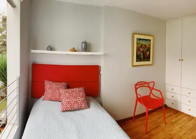 a bedroom with a red headboard and a red chair at Parque & Mar lindo alojamiento en San Isidro in Lima