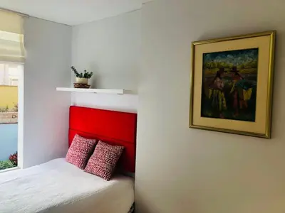 a bedroom with a bed with a red head board at Parque & Mar lindo alojamiento en San Isidro in Lima