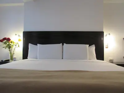 a bed with white pillows and a black headboard at Quilla House Ecologico in Machu Picchu