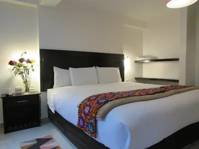 a bedroom with a large white bed with a black headboard at Quilla House Ecologico in Machu Picchu