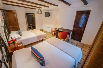 a hotel room with two beds and a desk at Vilas Insight Hotel Machupicchu in Machu Picchu