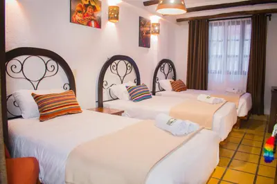 a hotel room with three beds with white sheets at Vilas Insight Hotel Machupicchu in Machu Picchu