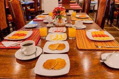a table with plates of food and cups of coffee at Vilas Insight Hotel Machupicchu in Machu Picchu