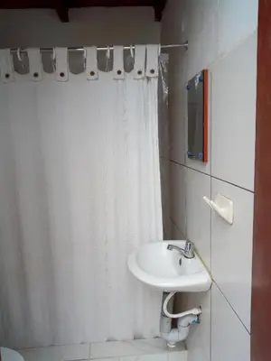 a bathroom with a white shower curtain and a sink at La Casa Maruja Habitación doble P in San Bartolo