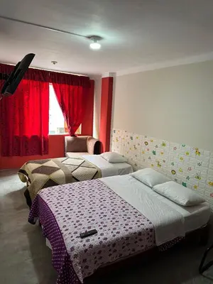 two beds in a room with red curtains at La Esquina de Doña Julia in Lima